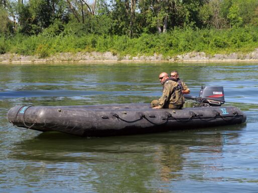 Zwei Soldaten fahren auf der Donau mit dem S-Boot.